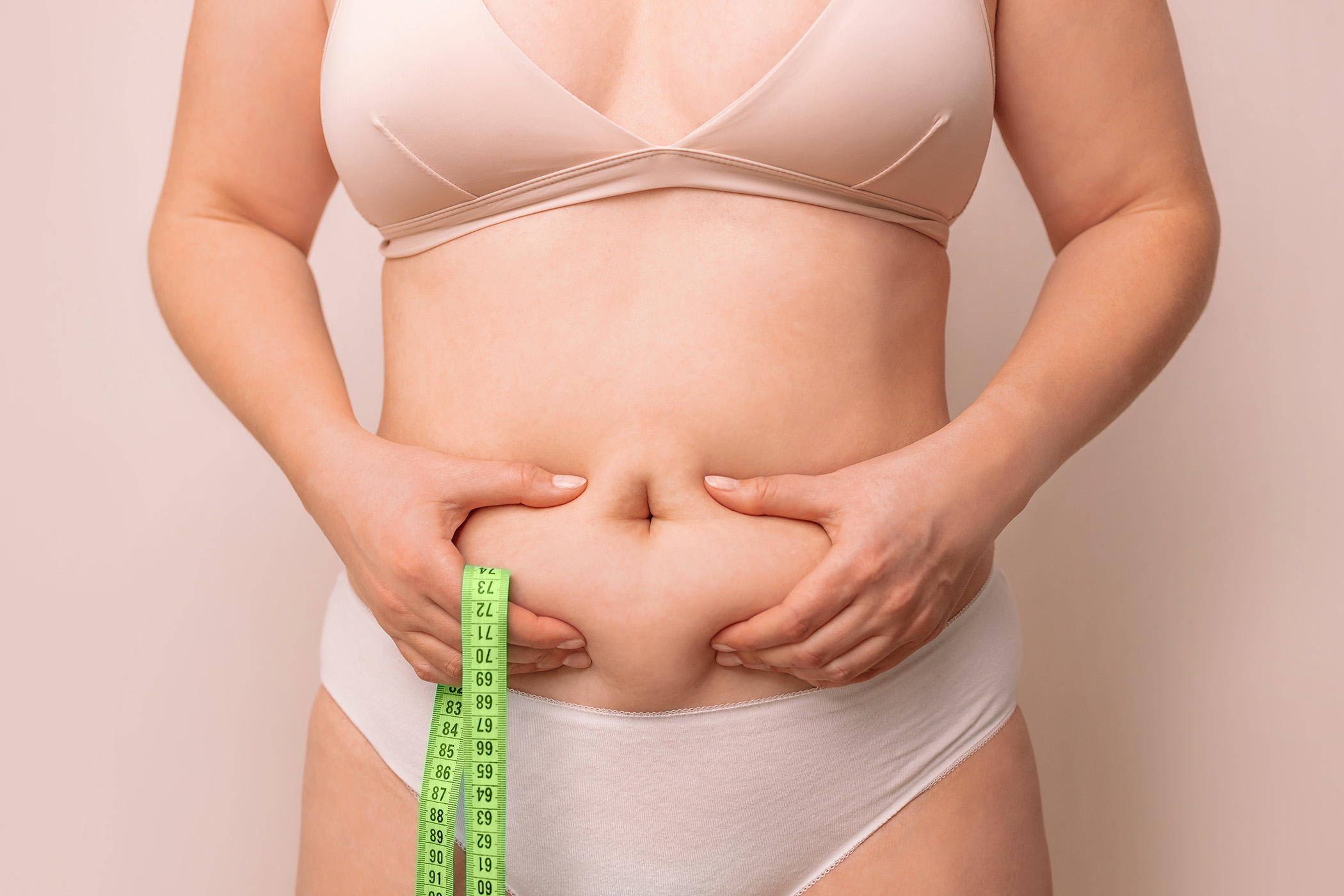 woman grabbing stubborn stomach fat
